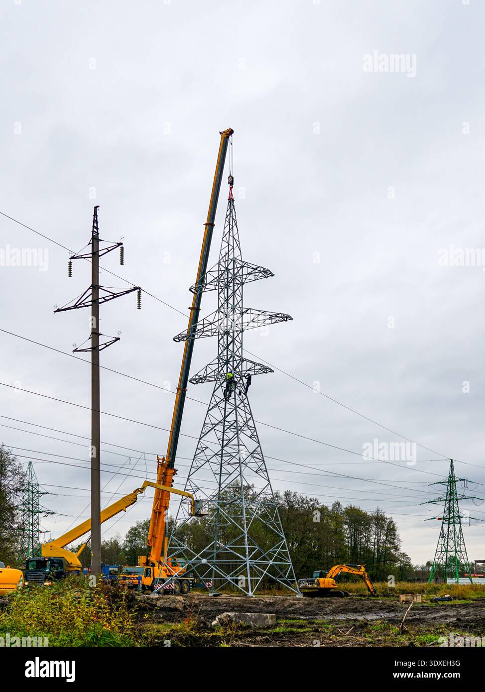 Installation des Hochspannungs-Übertragungsturms mit Kranen und Bauarbeitern Stockfoto