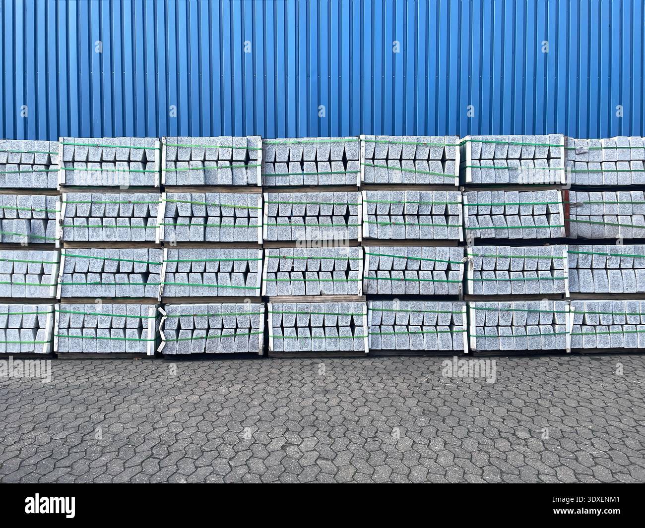 Gestapelte weiße Steine stehen vor einer blauen Wand auf Kopfsteinpflaster Stockfoto