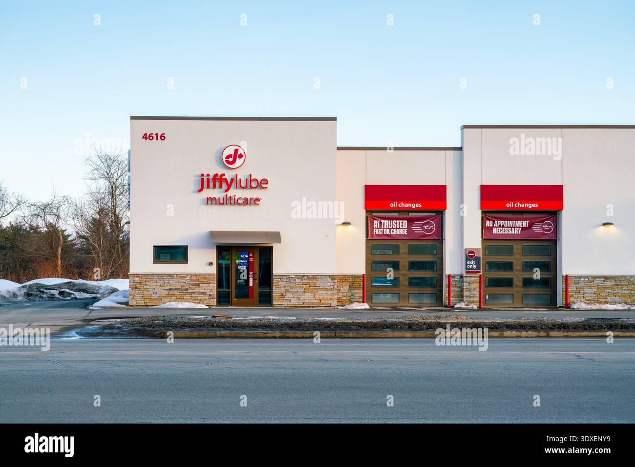 New Hartford, NY - 28. Februar 2026: Detaillierte Abendansicht des Jiffy Lube Multicare Service Centers mit roter Beschilderung, drei Ölwechselbuchten und Steinakzenten Stockfoto