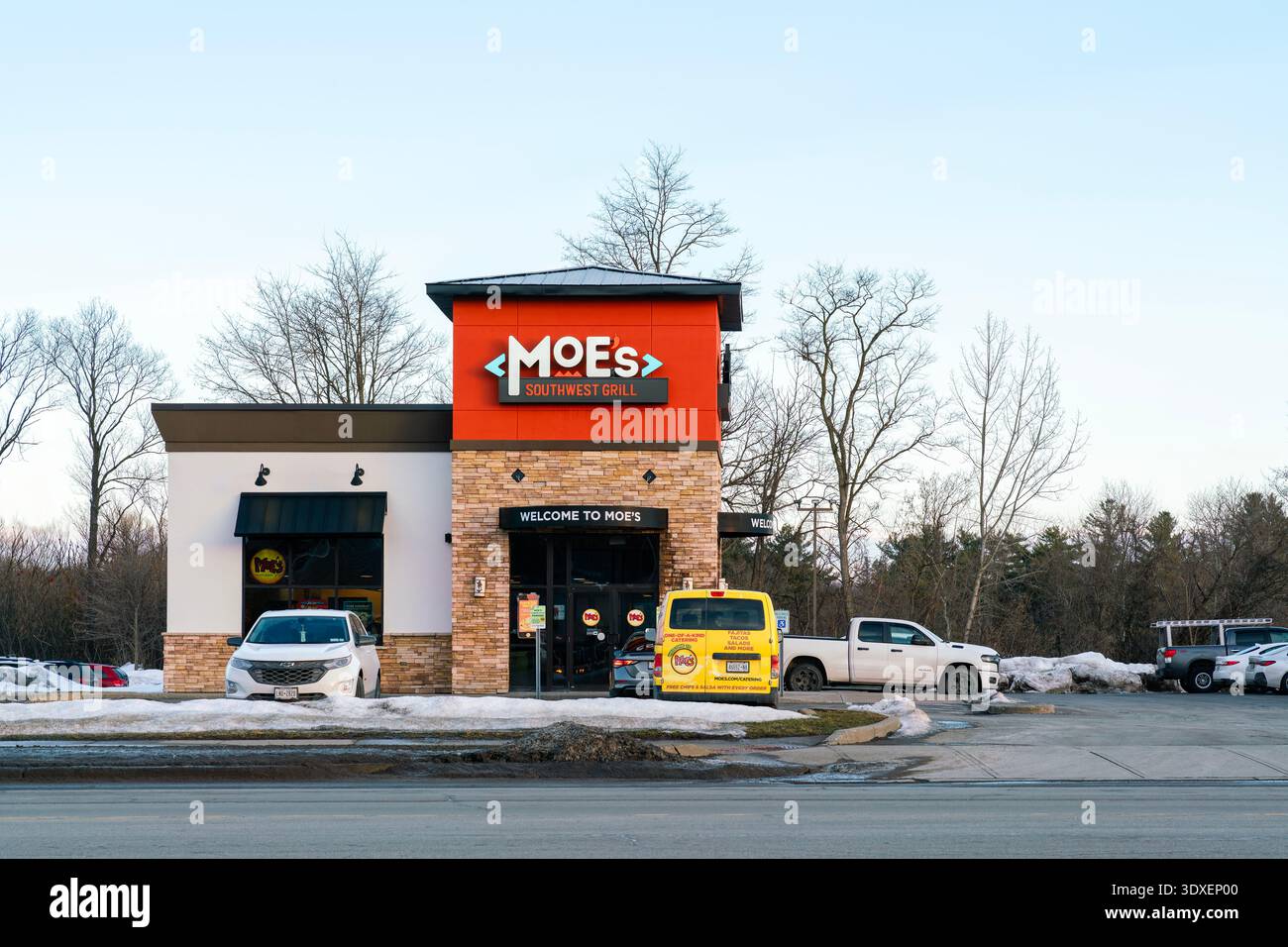 New Hartford, NY - 28. Februar 2026: Nächtlicher Blick auf Moe's Southwest Grill Restaurant mit „WELCOME TO MOE’s“-Eingangsschild und Winterlandschaft Stockfoto