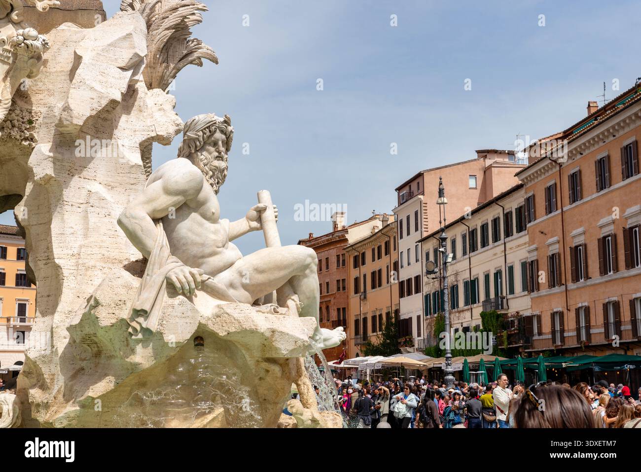 Rom, Italien – 20. April 2025: Aus nächster Nähe eine Marmorstatue am Brunnen Piazza Navona mit umliegenden historischen Gebäuden und dichten touristischen Aktivitäten Stockfoto