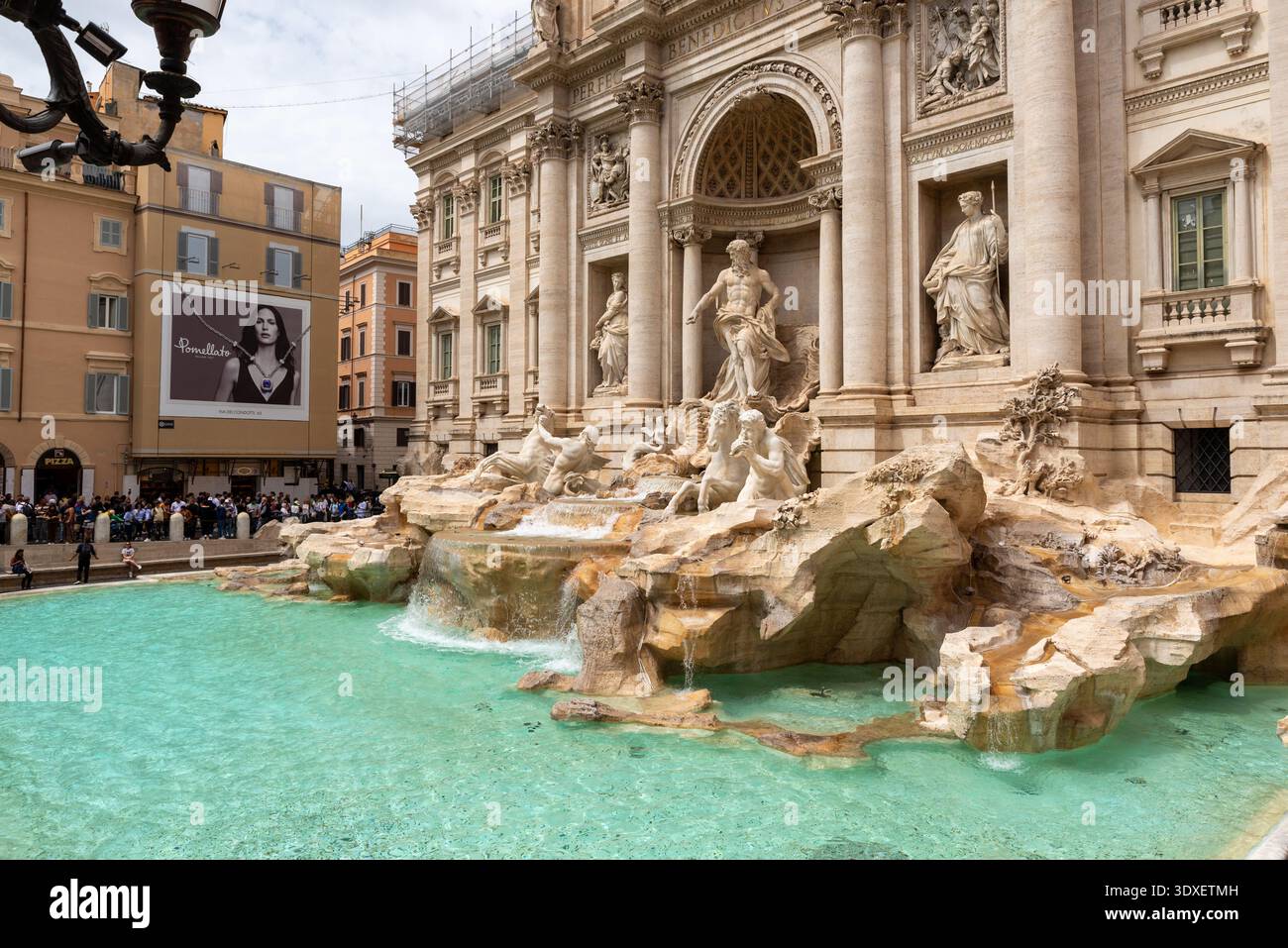 Rom, Italien – 20. April 2025: Besucher erkunden den Trevi-Brunnen und machen Fotos von der prunkvollen barocken Fassade und dem kaskadierenden Wasser unter hellen Spitzen Stockfoto