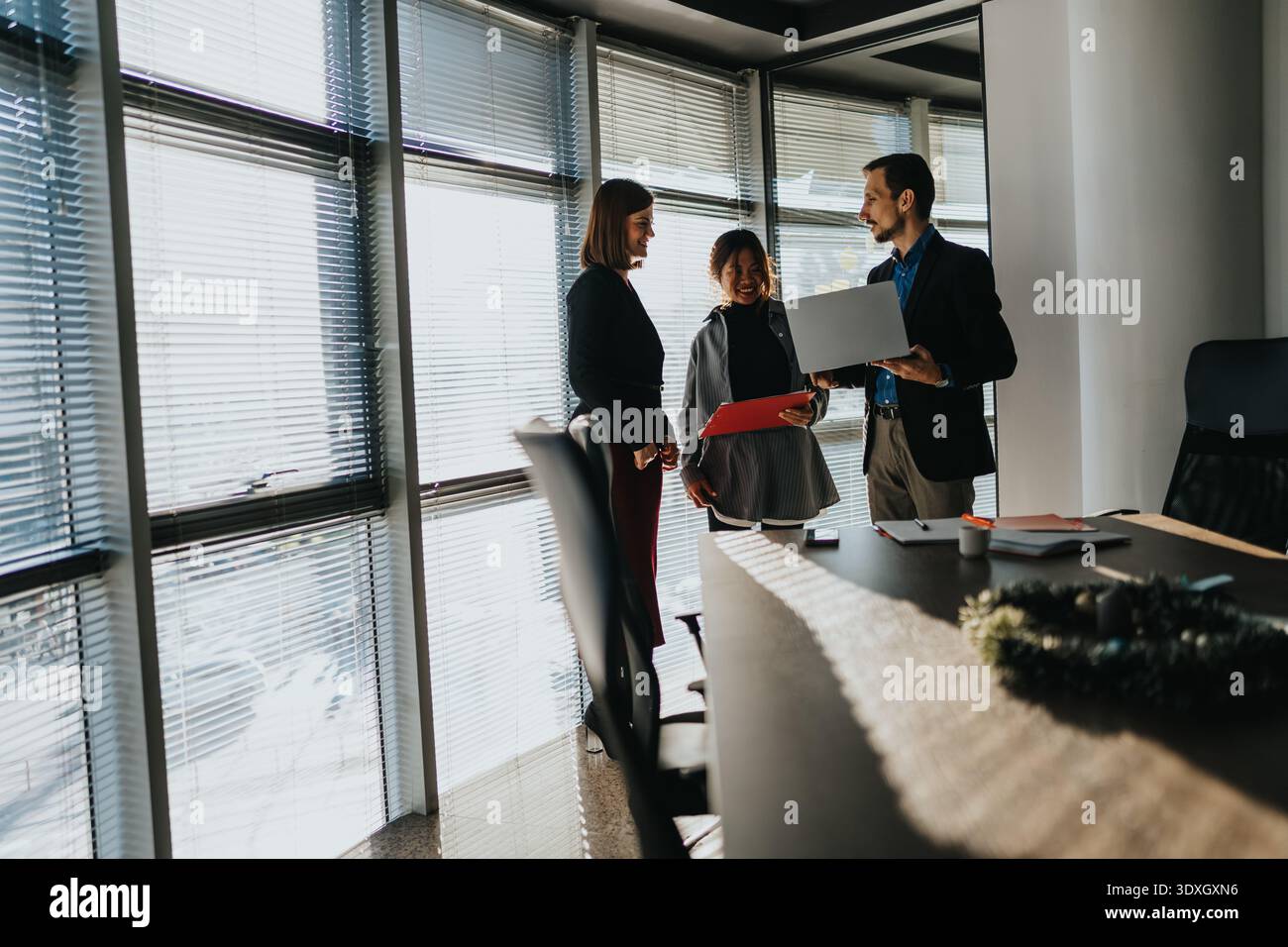 Geschäftskollegen diskutieren ein Projekt neben einem Laptop in einem hellen, modernen Büro Stockfoto