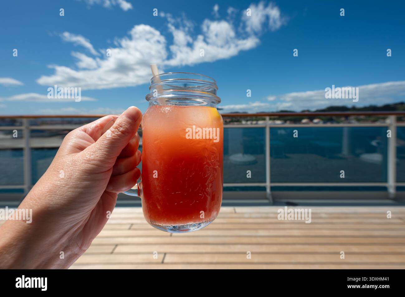 Ein Glas frischer Grapefruitsaft in der Hand. Erfrischendes Getränk im Kreuzfahrturlaub. Stockfoto