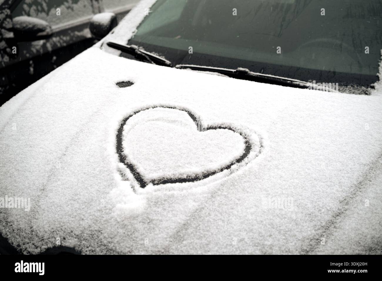 Das Herz auf der Motorhaube eines schneebedeckten Autos Stockfoto