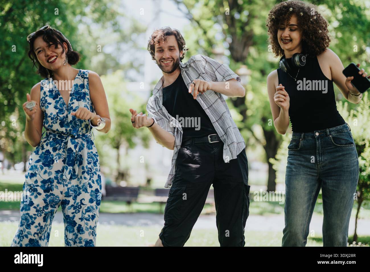 Drei Freunde tanzen im Park und genießen gemeinsam einen sonnigen Tag Stockfoto