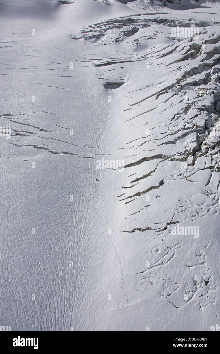 Bergsteiger, die über den Mont Blanc-Gletscher wandern, in einer atemberaubenden alpinen Eislandschaft zusammengeschnallt. Stockfoto