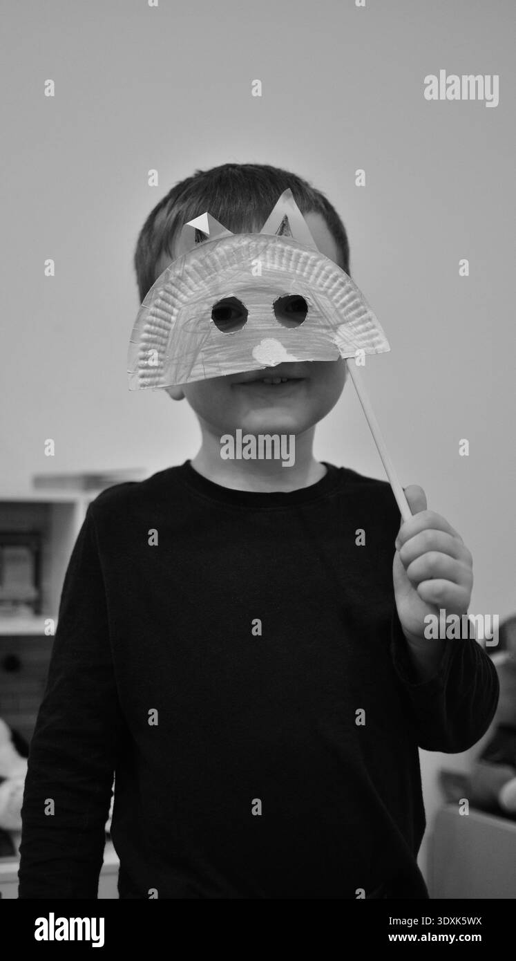 Kreativer Kleinkinder mit handgefertigtem Papierteller Tiermaske in Schwarz-weiß-Foto. Kindheit, Kunst und Handwerk zu Hause, Spiel Stockfoto
