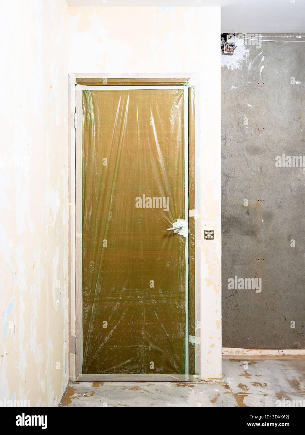 Tür mit Schutzfolie im für die Renovierung vorbereiteten Zimmer Stockfoto