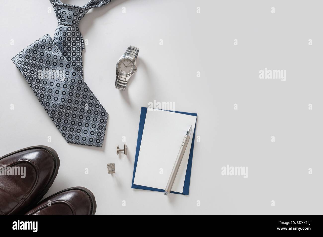 Krawatte, Uhr, Schuhe, Manschettenknöpfe und Karte auf hellem Hintergrund angeordnet. Vatertag-Konzept. Geschäftsfeier. Minimalistischer Stil. Stockfoto