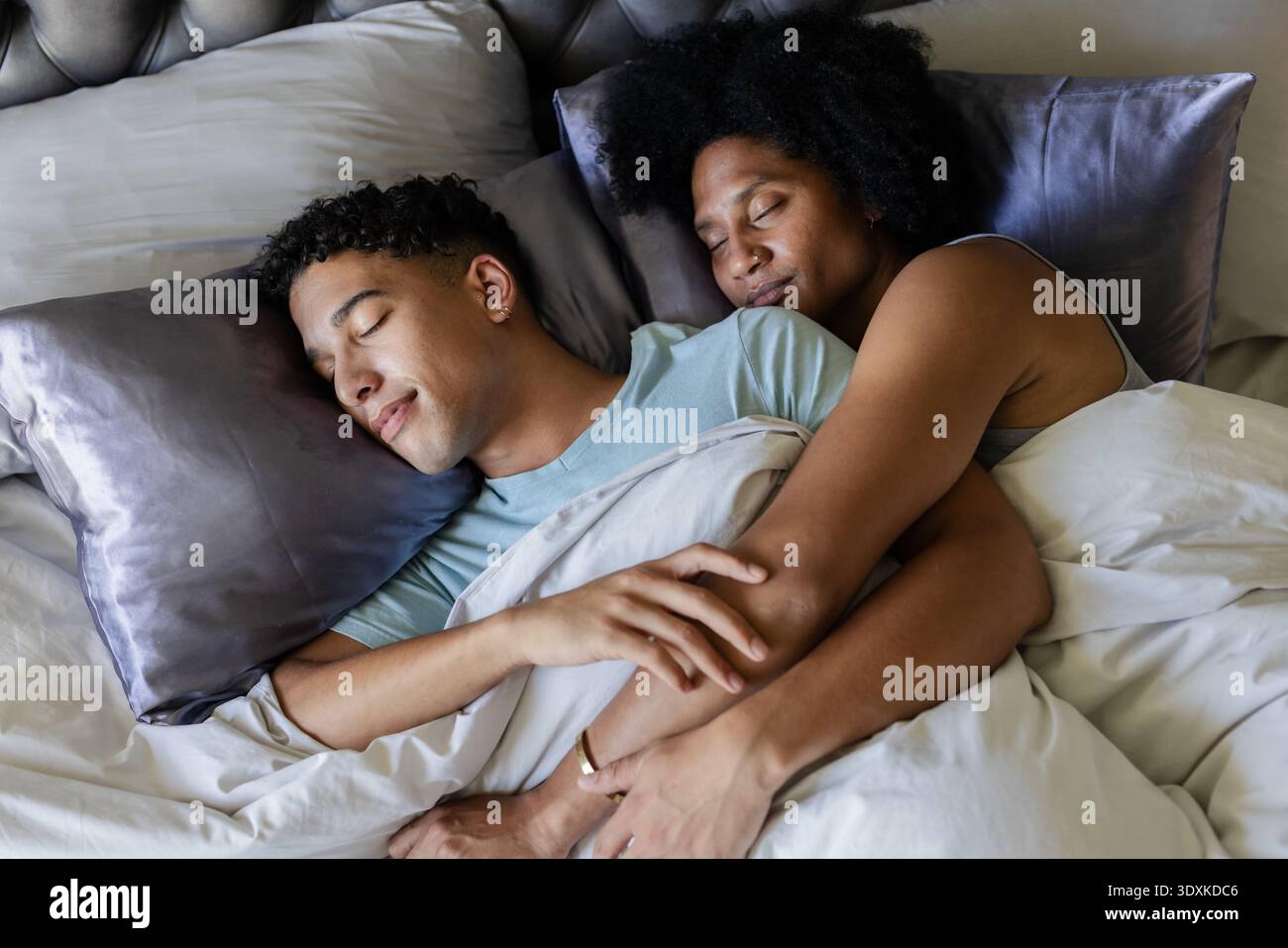 Afroamerikanisches Paar, das sich im Bett hält und mit weißer Bettdecke, goldener Ring sichtbar Stockfoto