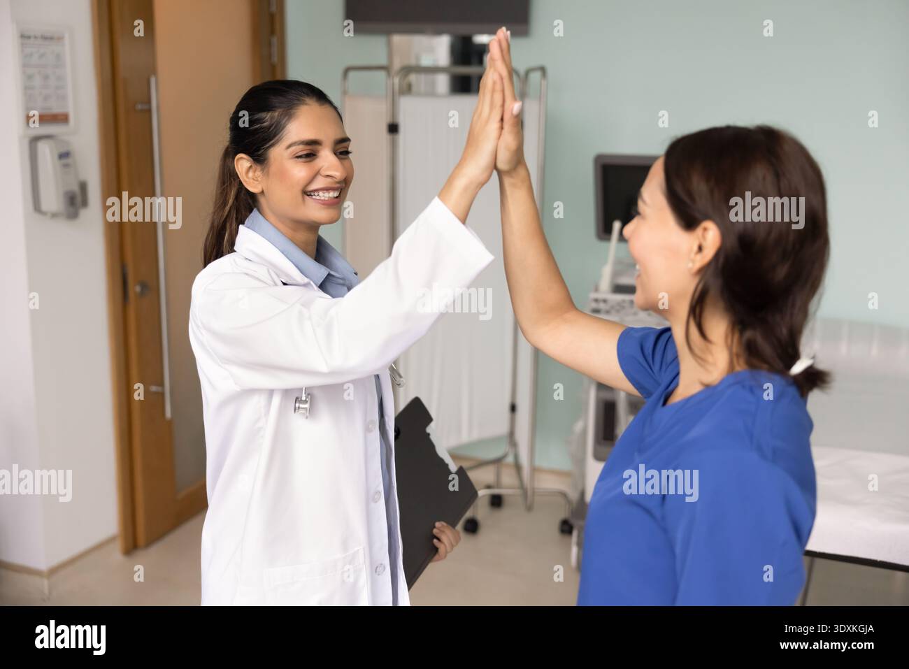 Zwei Ärztinnen, die in der Klinik hohe fünf Gesten austauschen Stockfoto