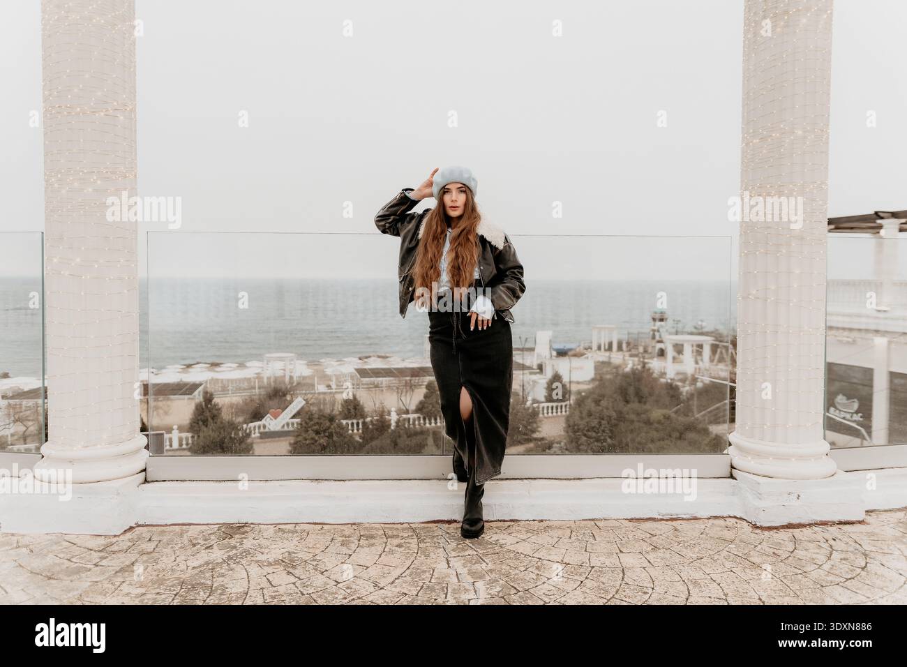 Modeporträt der Frau stilvolles Mädchen in Lederjacke und Baskenmütze posiert auf der Terrasse in Sewastopol Krim mit Blick auf das Meer Stockfoto