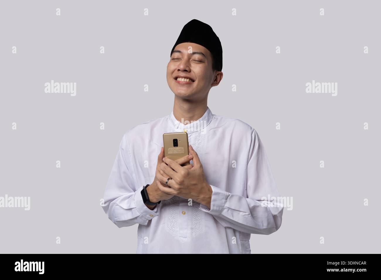 Ruhiges Individuum, das Telefon mit zärtlichem Ausdruck in der Nähe hält Stockfoto