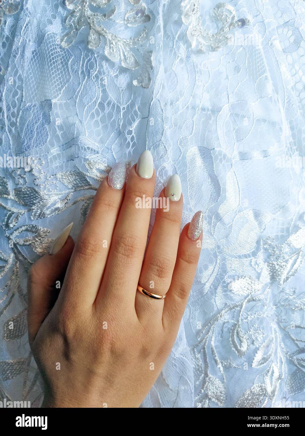 weiße Spitze mit Mustern Stoff eines Hochzeitskleides Nahaufnahme Makro Vollbild Hintergrundtapete weißer Stoff Spitzenstoff. weibliche Hände mit einem en Stockfoto