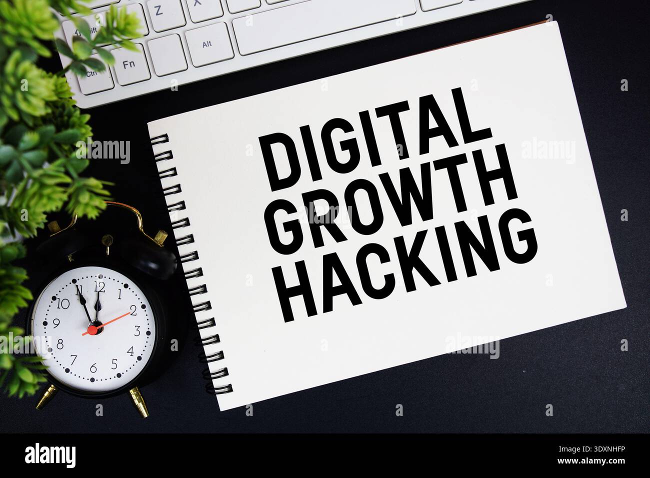 Digital Growth Hacking Text auf Notizblock mit Tastatur und Wecker auf schwarzem Hintergrund Stockfoto