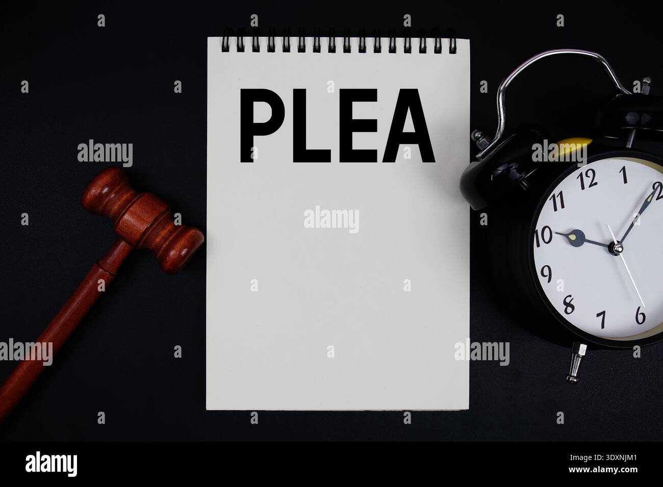 PLÄDOYER auf Notizblock mit Hamel und Wecker auf schwarzem Hintergrund Stockfoto