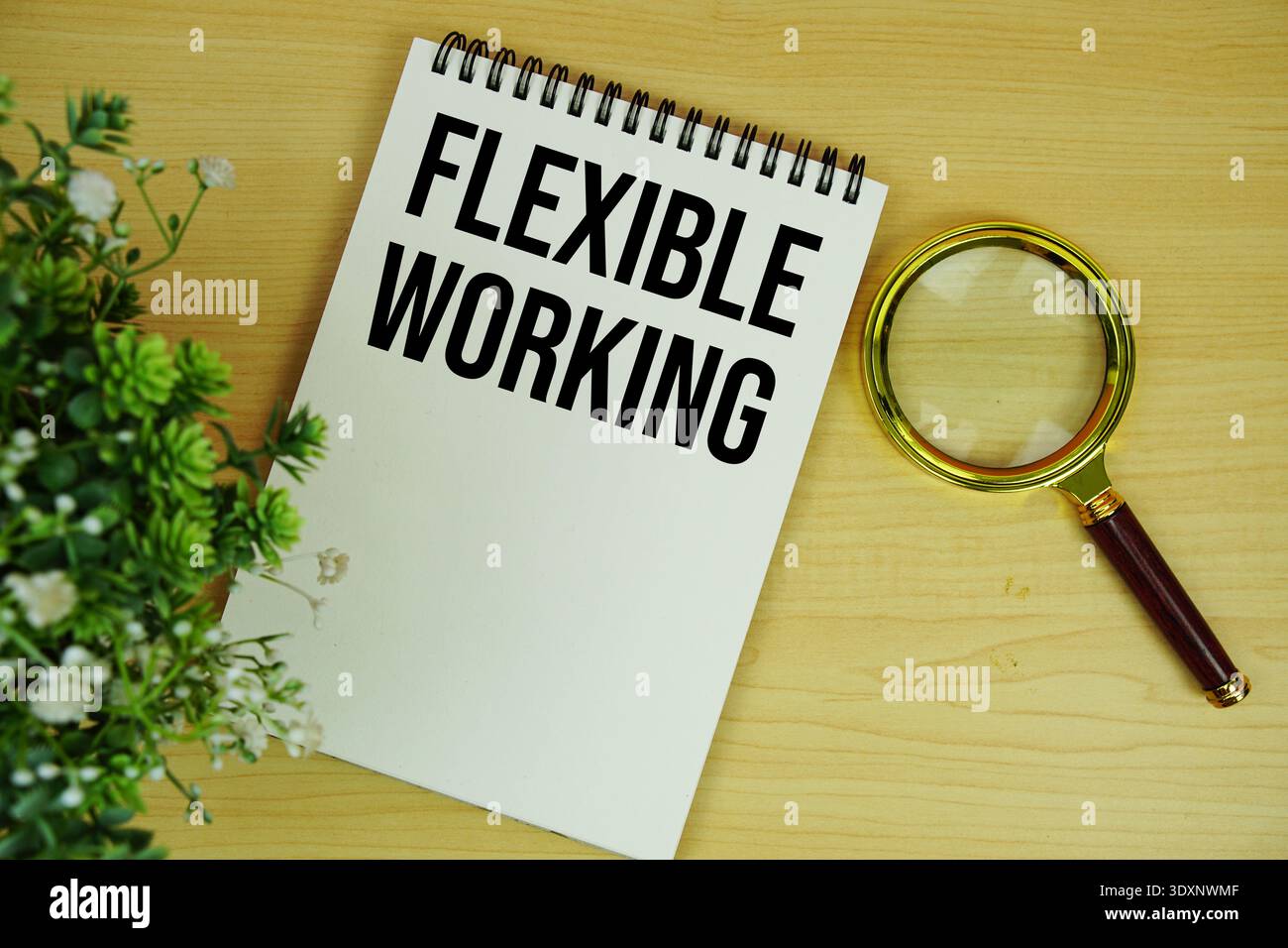 Flexibler Arbeitstext auf Notizblock mit Lupe flach auf hölzernem Hintergrund Stockfoto