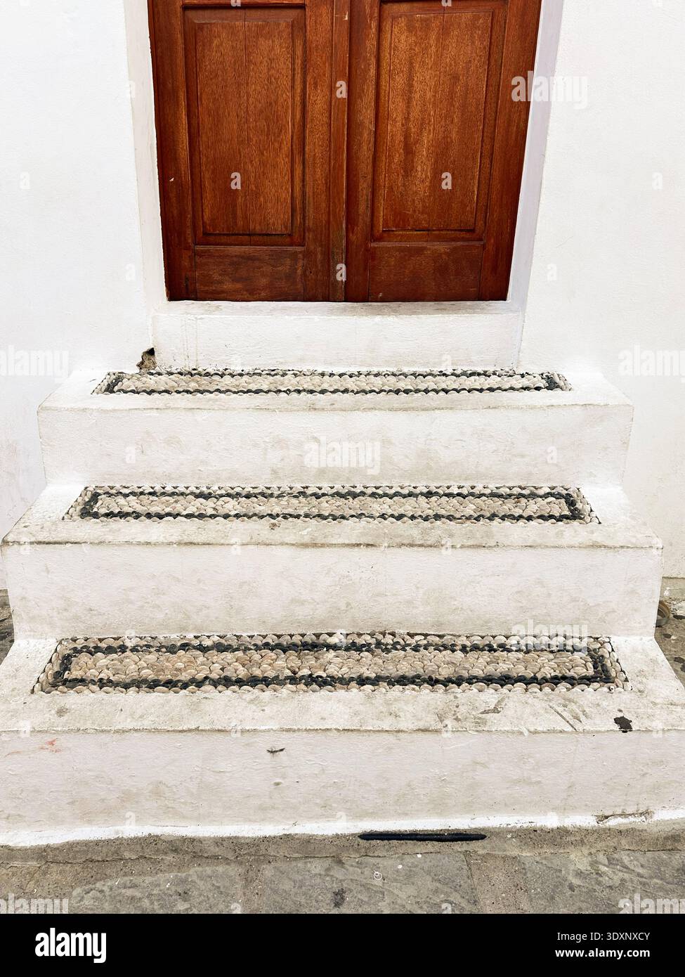 Die hölzerne Eingangstür, erreicht über eine mit kleinen Kieselsteinen gepflasterte Treppe, Rhodos, Griechenland Stockfoto