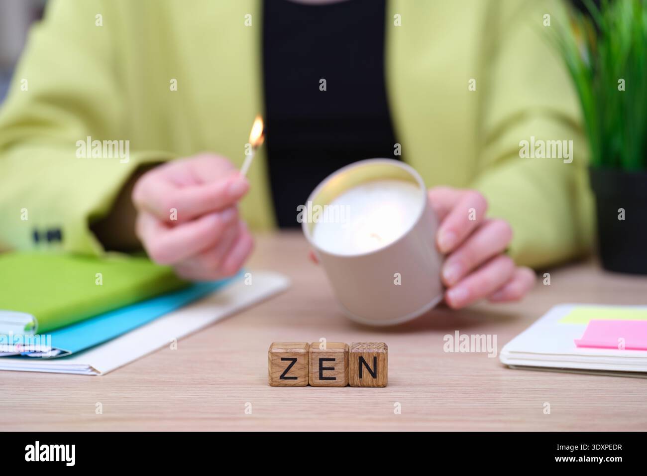 Schaffen Sie eine beruhigende Atmosphäre mit einer beleuchteten Kerze und genießen Sie Ruhe und Konzentration in einem modernen Arbeitsbereich Stockfoto