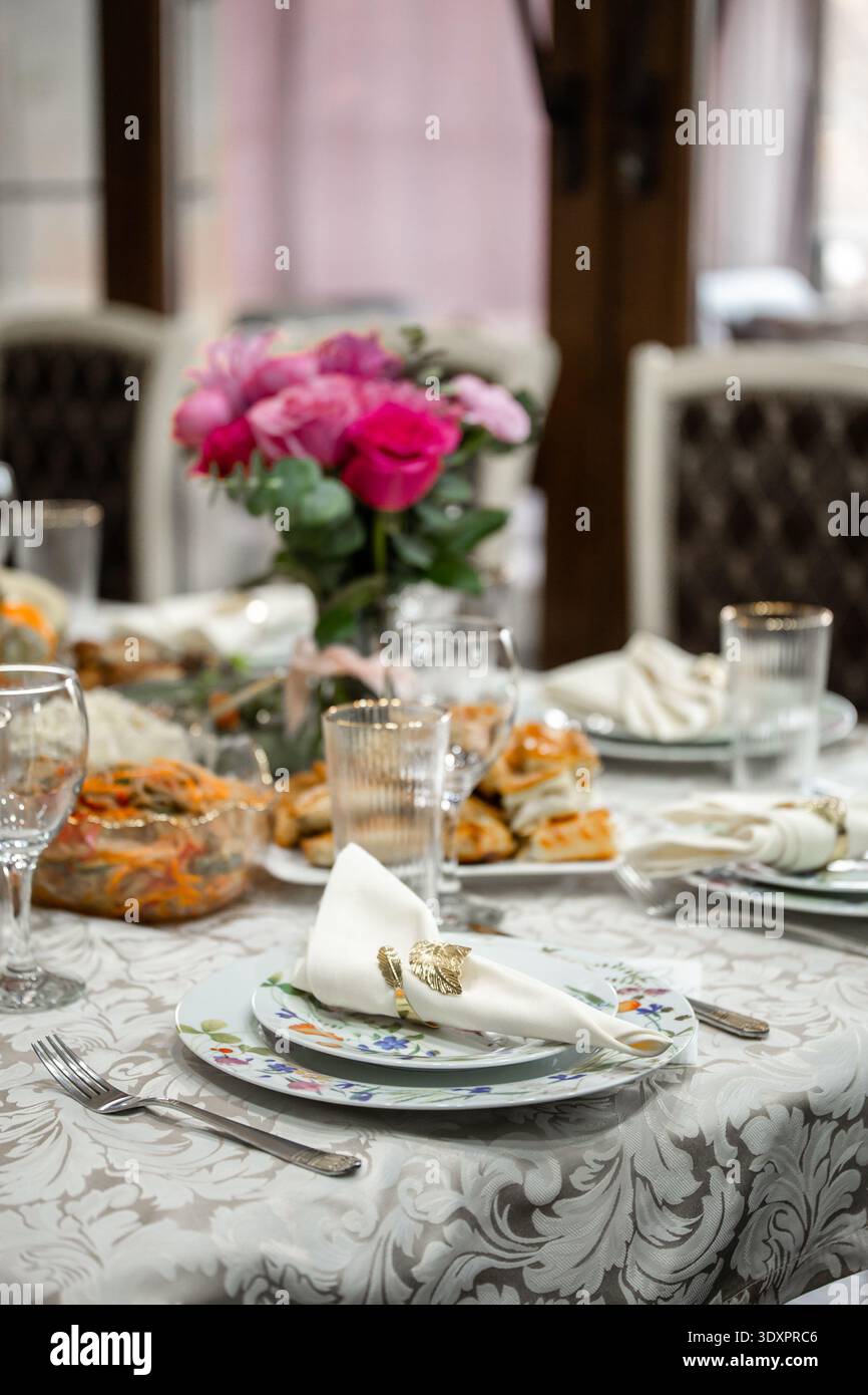Eleganter Tisch mit rosafarbenen Rosen und Vorspeisen Stockfoto