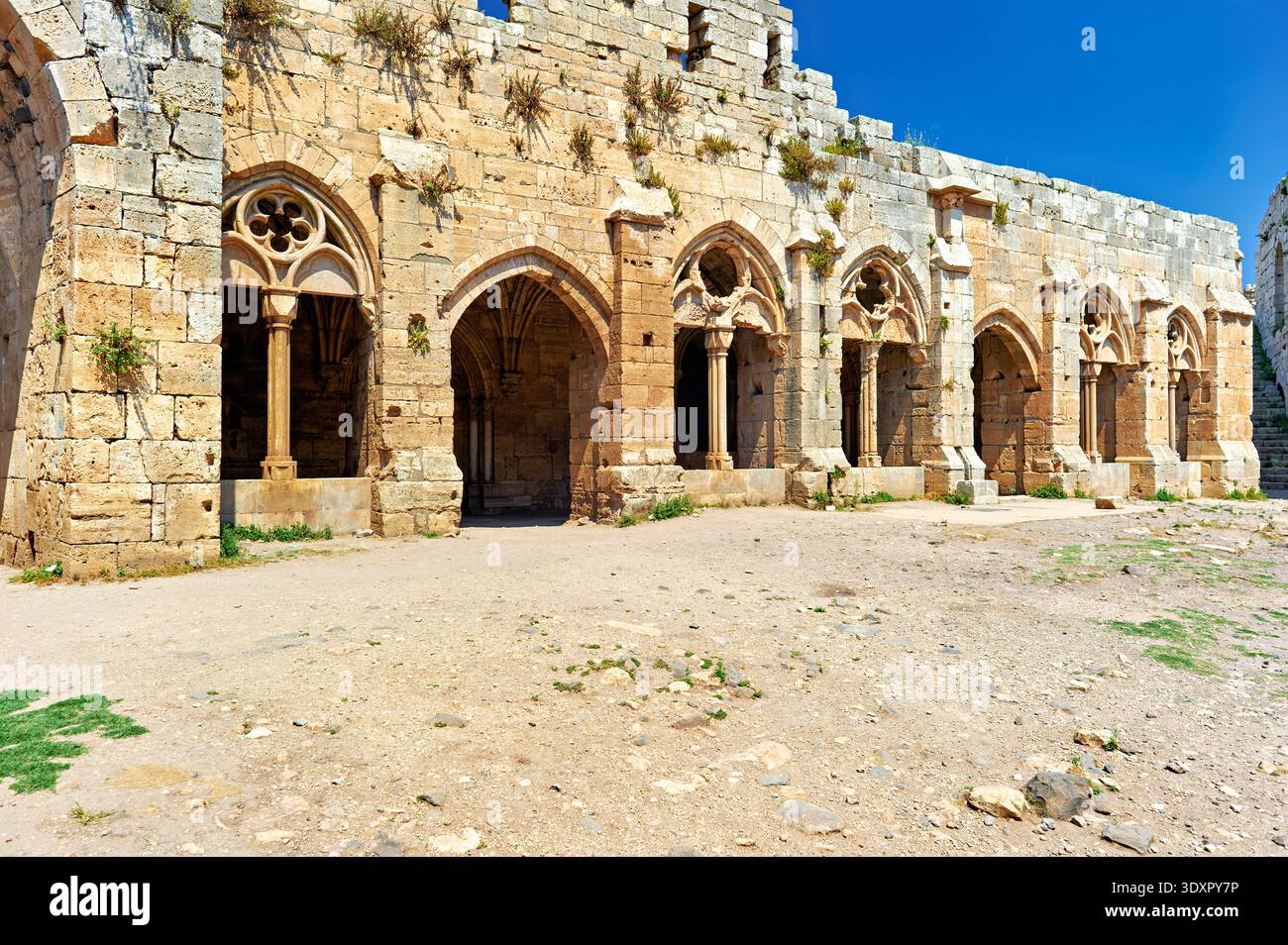 Besucher erkunden die historischen Bauten des Krak des Chevaliers in Syrien. Diese Burg zeigt Mauern aus Stein und antike Architektur. Stockfoto