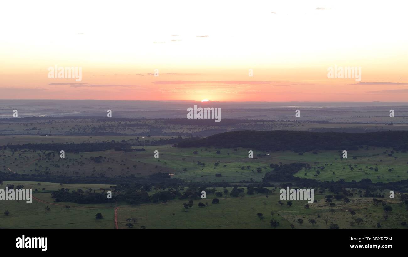Drohnenlandschaft mit Sonnenaufgang über sanften Weidefeldern und ländlichem Ackerland mit Morgenlicht, das das ländliche Gelände beleuchtet. Stockfoto
