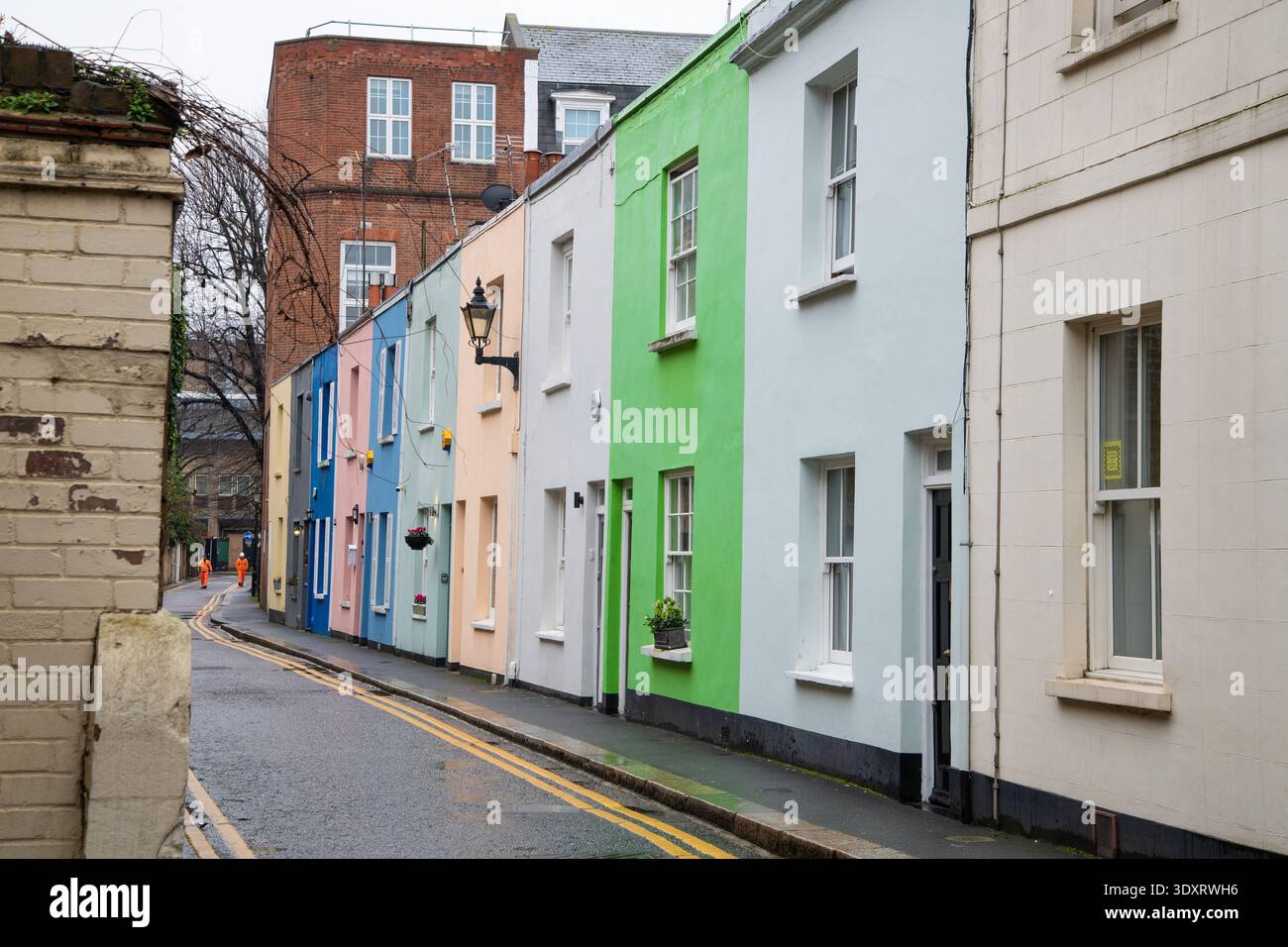 Eine Reihe von bunten Reihenhäusern in einem Kensington-Miws, London. Charmante, enge Wohnstraße mit pastellfarbenen Fassaden und klassischer britischer Architektur Stockfoto