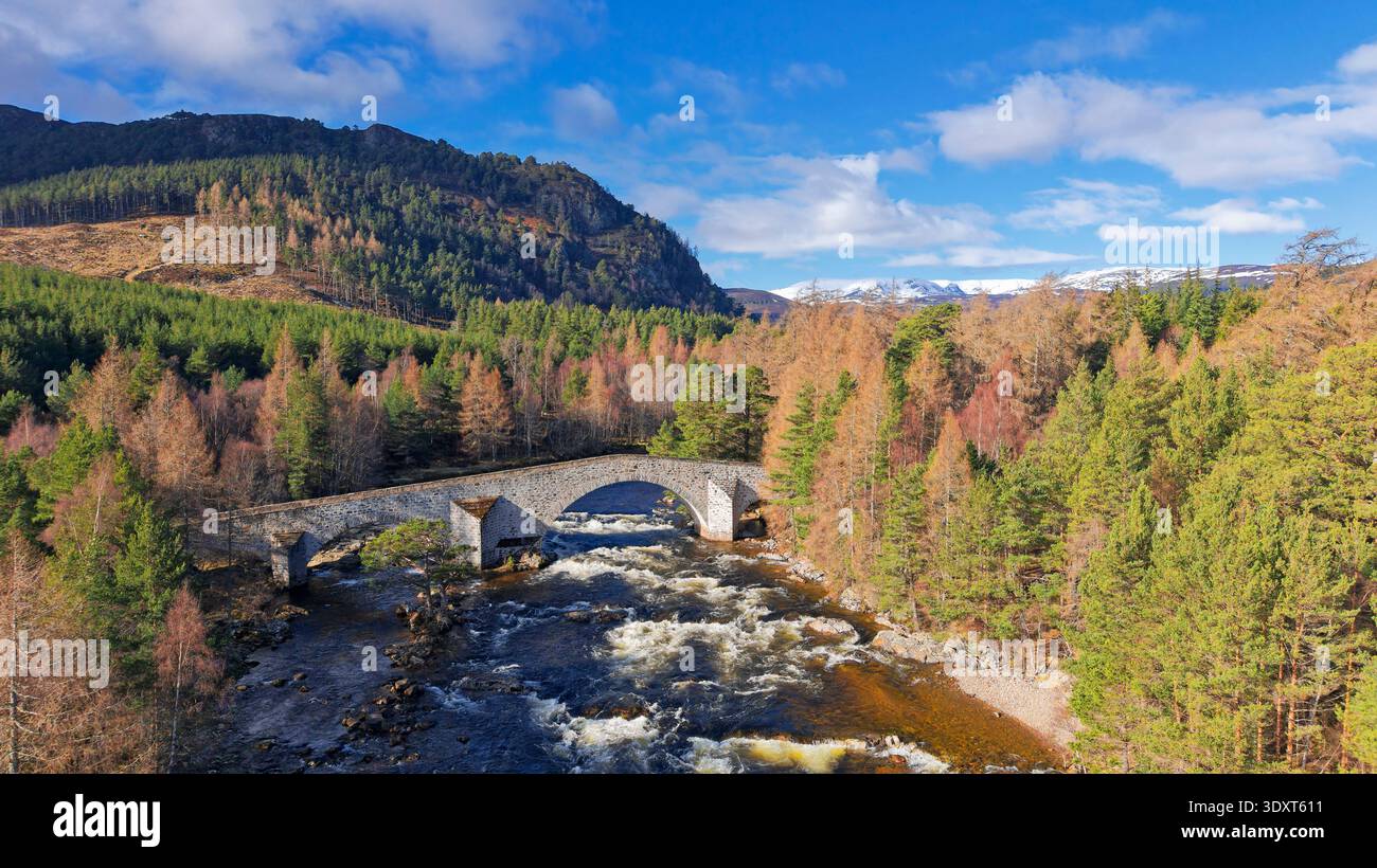 Old Bridge of Dee Braemar Scotland errichtete 1753 blauen Himmel und Sonnenschein über der Brücke und Bäume Schnee auf den Bergen Stockfoto