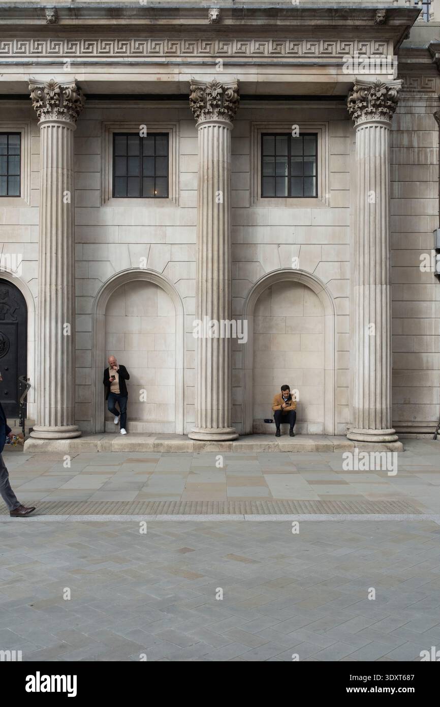 Männer auf Handys bei der Bank of England, London. Ein Moment der Pause inmitten des finanziellen Herzens der Stadt. Stockfoto