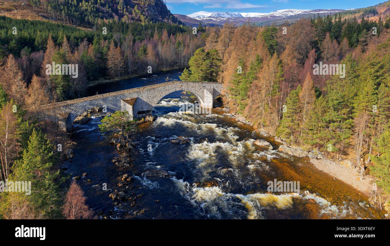 Old Bridge of Dee Braemar Scotland errichtete 1753 Sonnenschein über der Brücke und Bäume schneebedeckten Berge Stockfoto