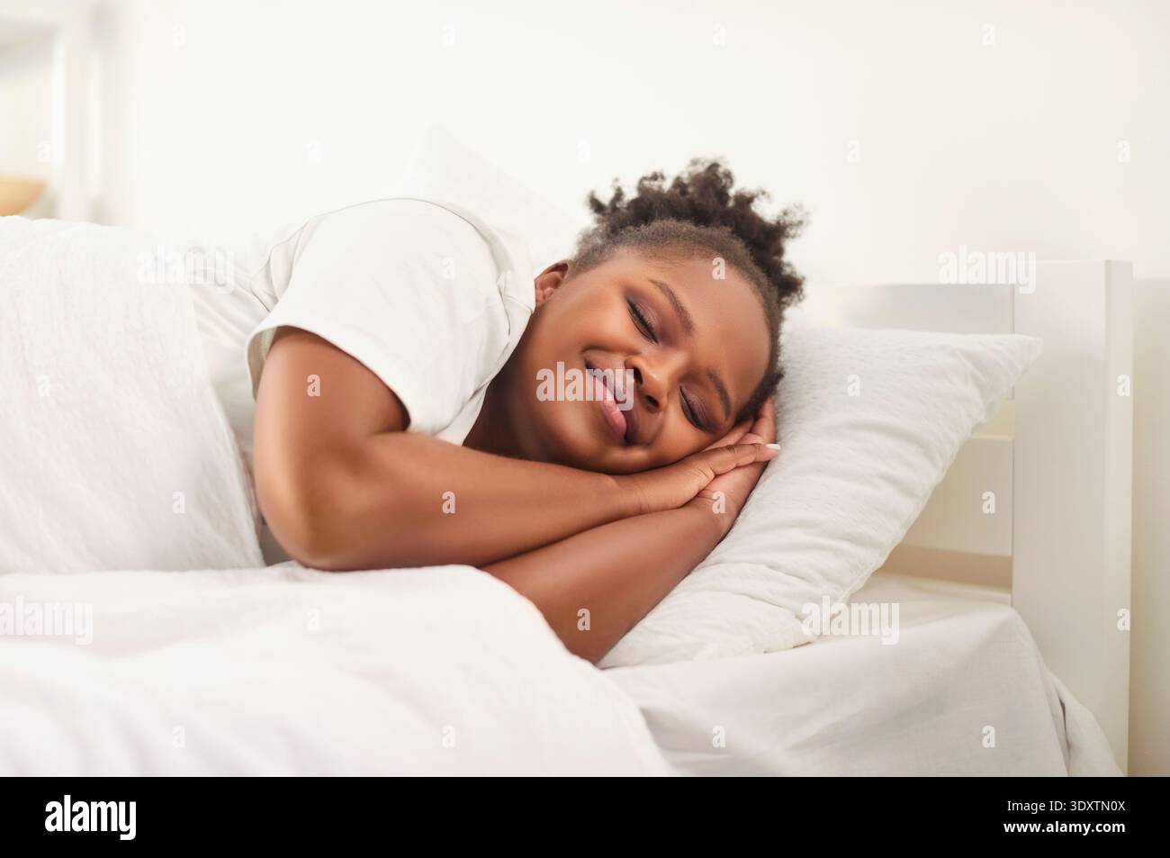 afroamerikanerin schläft gut in einem bequemen Bett, liegt auf weichem Kissen, orthopädischer Matratze Stockfoto