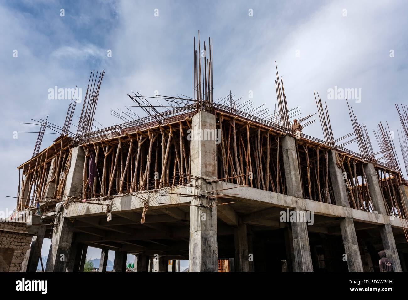 Baustelle in Leh, die den Betonrahmen eines mehrstöckigen Gebäudes mit Holzgerüsten und Stahlverstärkungsstäben zeigt. Stockfoto