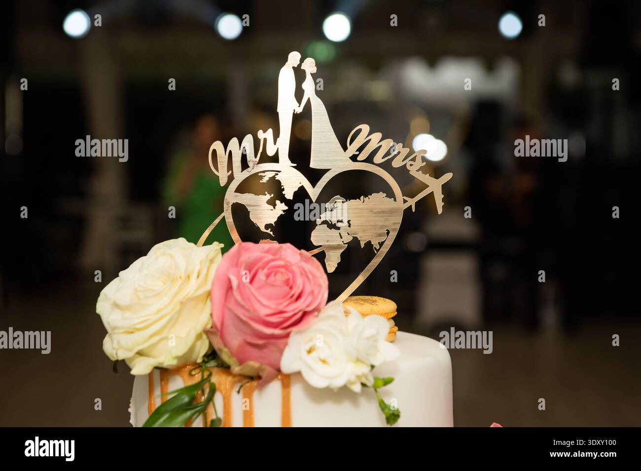 Hochzeitstortenauflage im Reisestil ist eine personalisierte Acryl- oder Holzdekoration mit der Silhouette einer Braut und eines Bräutigams, einer herzförmigen Weltmutter Stockfoto