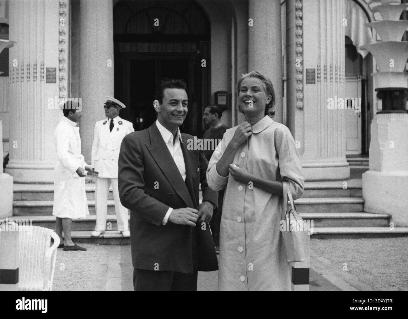 Der französische Schauspieler ROLAND LESAFFRE mit GRACE KELLY vor dem Carlton Hotel in Cannes während der Dreharbeiten zu TO CATCH A THIEF 1955 Regisseur ALFRED HITCHCOCK Roman DAVID DODGE Drehbuch JOHN MICHAEL HAYES Music LYN MURRAY Kostüm Design EDITH KOPF Paramount Pictures Stockfoto