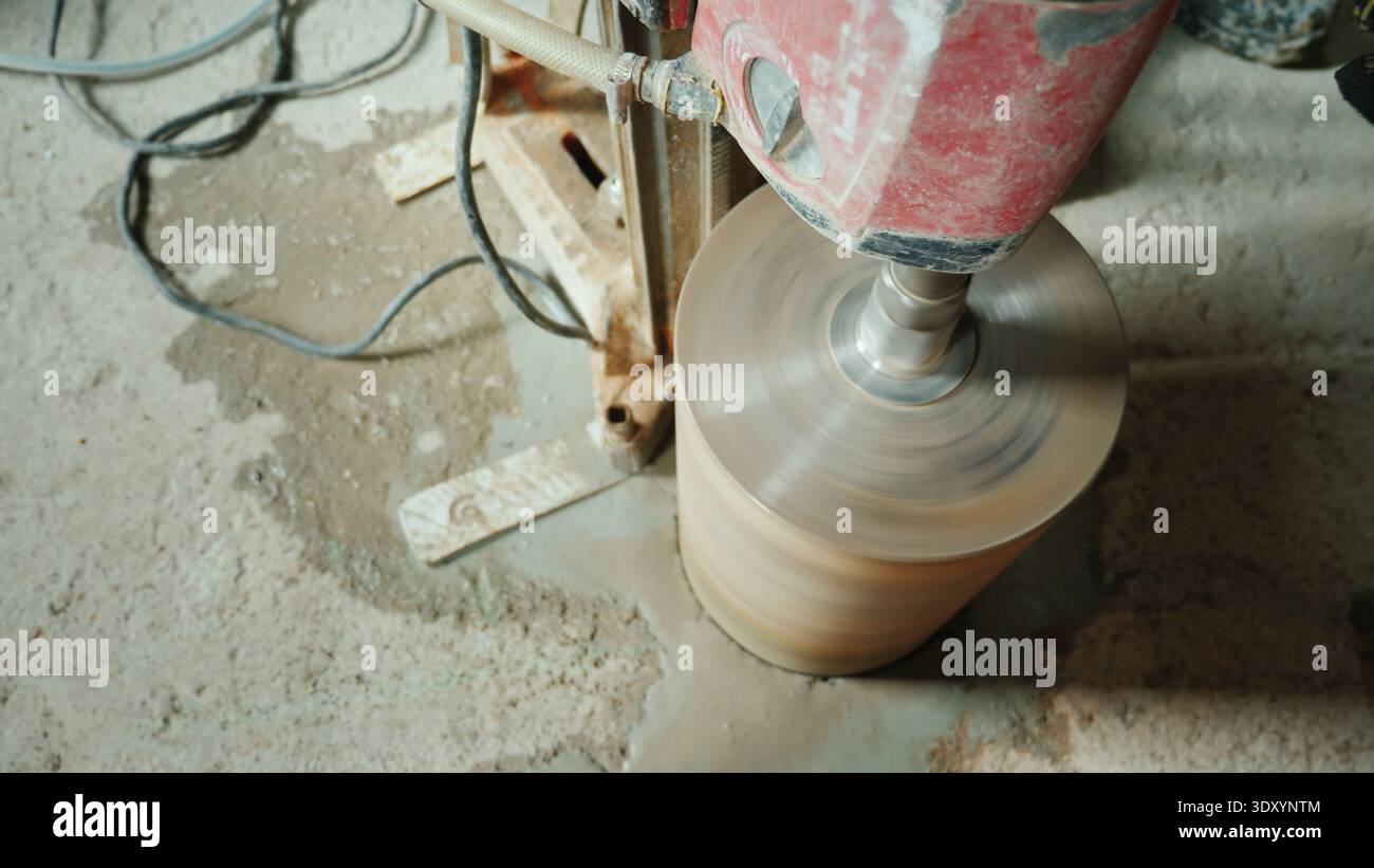 Der Baumeister bohrt Löcher in den Betonvorhang für die Verlegung von Lüftungsrohren und Rohrleitungen Stockfoto