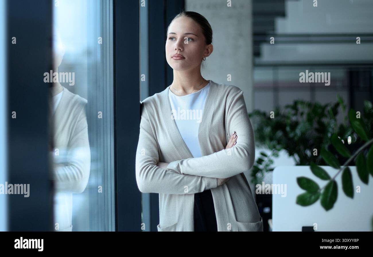 Eine Frau im Business-Anzug steht vor einem Fenster Stockfoto