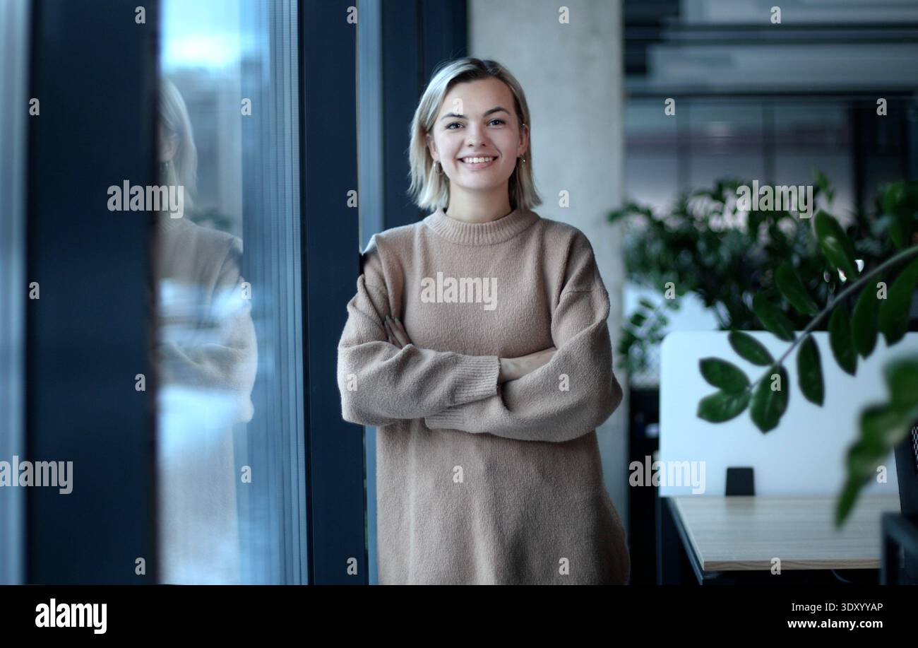 Eine Frau steht vor einem Fenster mit einer Pflanze im Hintergrund Stockfoto