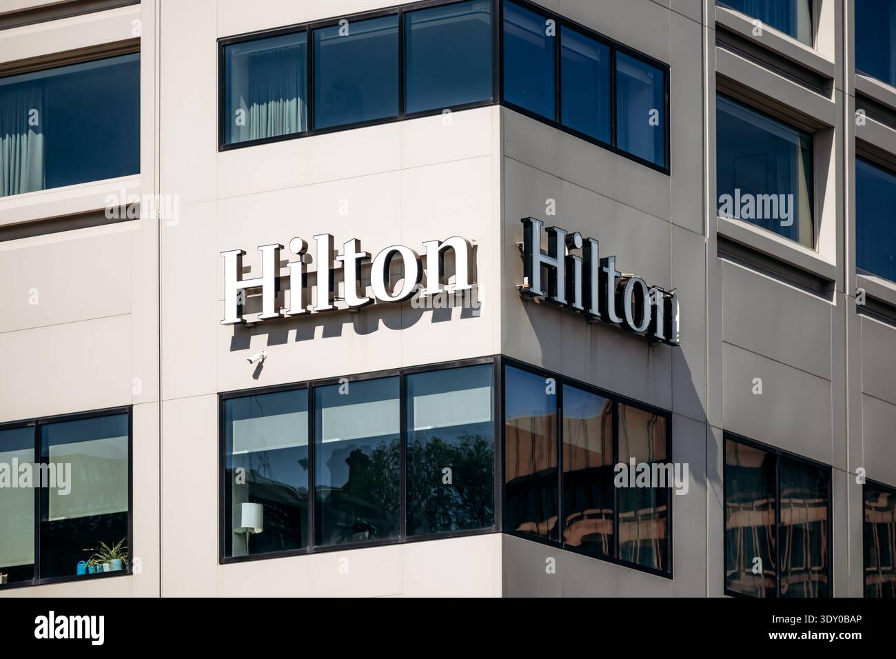 Quebec City, Kanada - 23. August 2025: Silbernes Logo des Hilton Hotels auf der weißen Ecke des modernen Gebäudes mit blau getönten Fenstern und Vorhängen Stockfoto