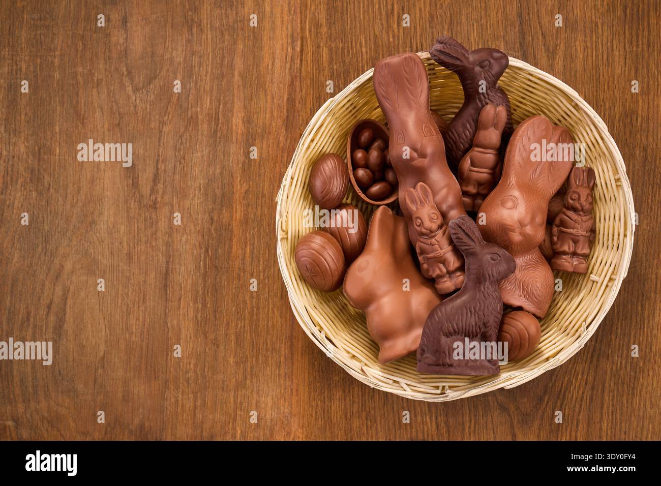 Schokoladen-osterhasen und Eier im Korb auf Holz Stockfoto