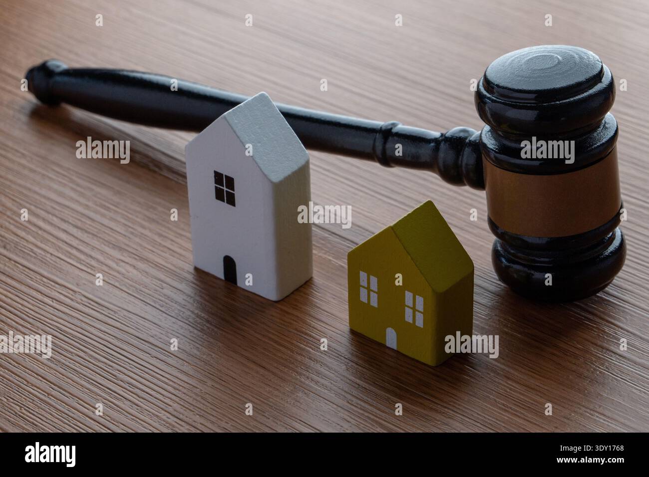Ein Hammer und zwei kleine Holzhäuser. Immobilienrecht, Immobilienstreitigkeiten, Nachlassplanung, Scheidungsabschlüsse und Wohnungsmarktvorschriften Stockfoto