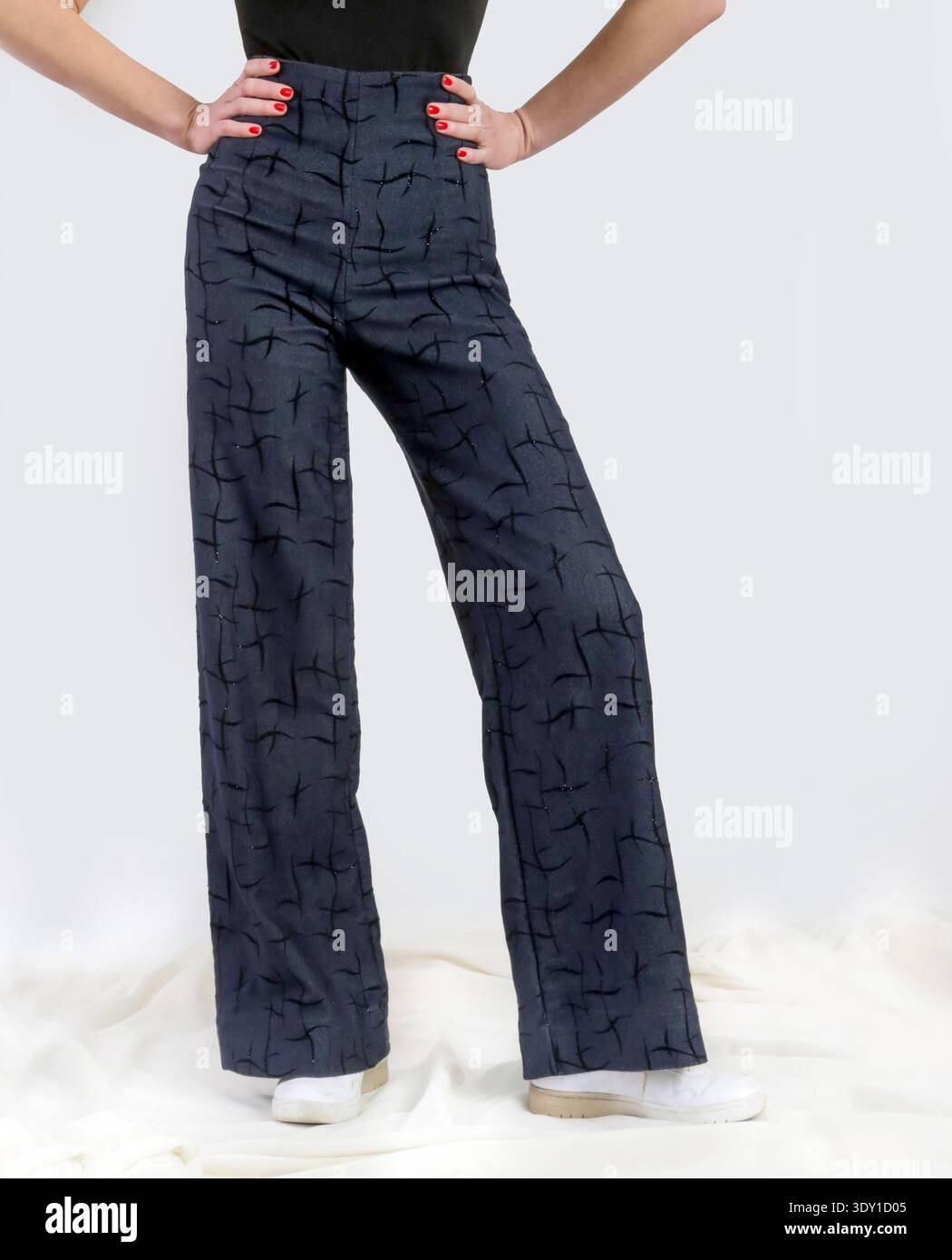 Stilvolle Frau mit gemustertem High-Waist Denim und schwarzem Body Contemporary Fashion Studio Konzept Stockfoto