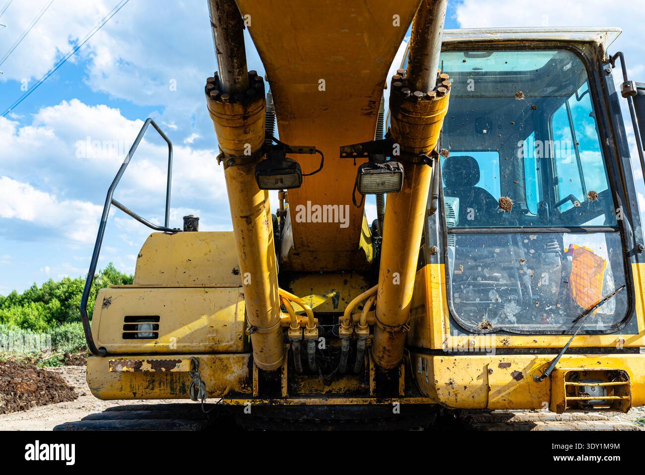 Gelber Hydraulikbagger, der auf einer Baustelle unter blauem Himmel betrieben wird Stockfoto