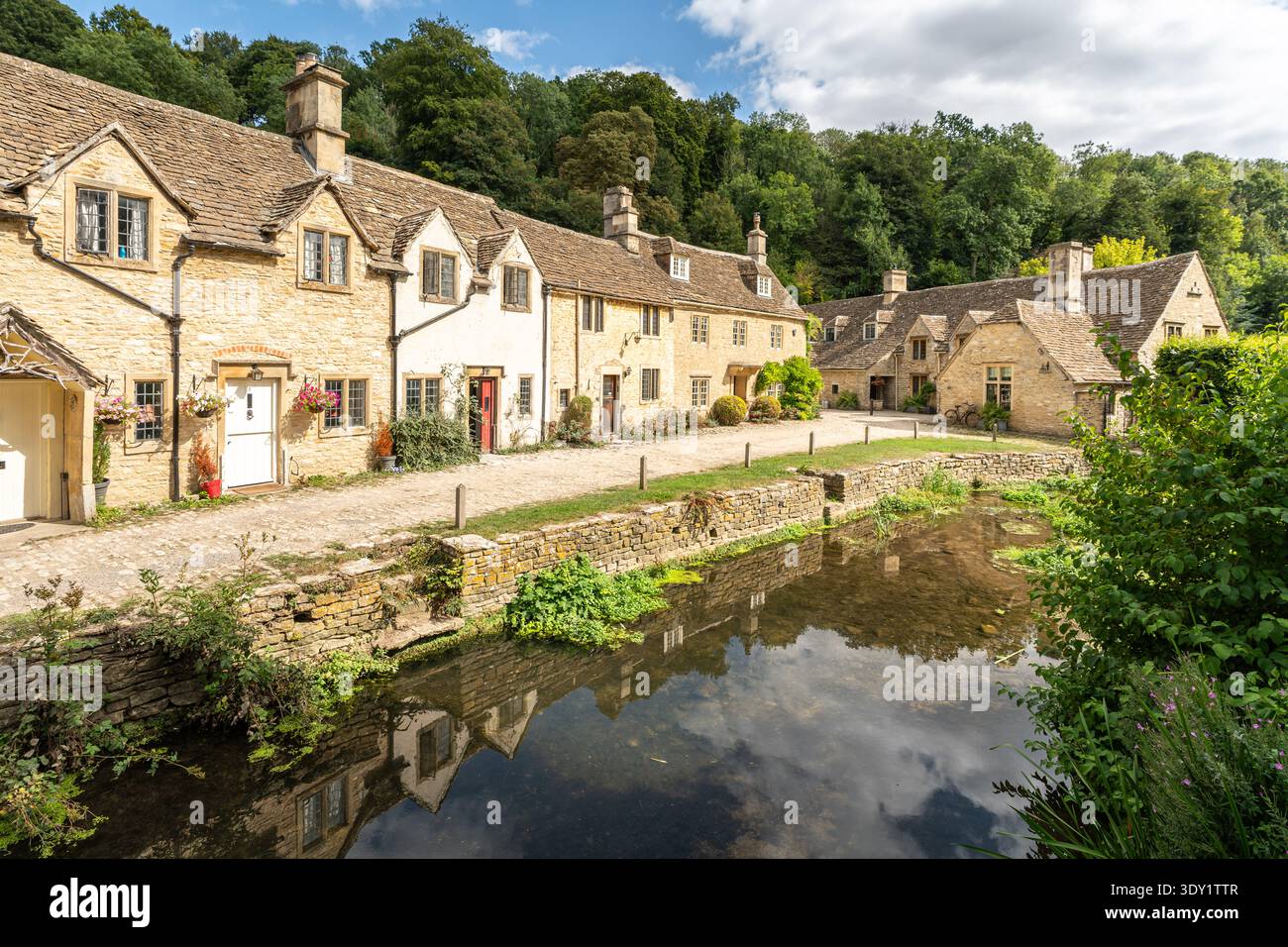Malerische Steinhäuser spiegeln sich in den ruhigen Gewässern des Bybrook River in Castle Combe, Cotswolds, England Stockfoto