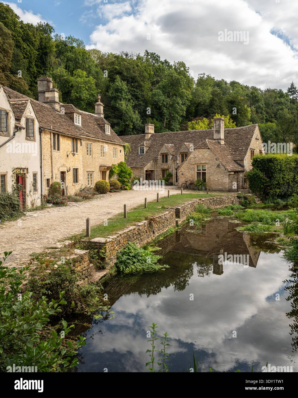 Malerische Steinhäuser spiegeln sich in den ruhigen Gewässern des Bybrook River in Castle Combe, Cotswolds, England Stockfoto