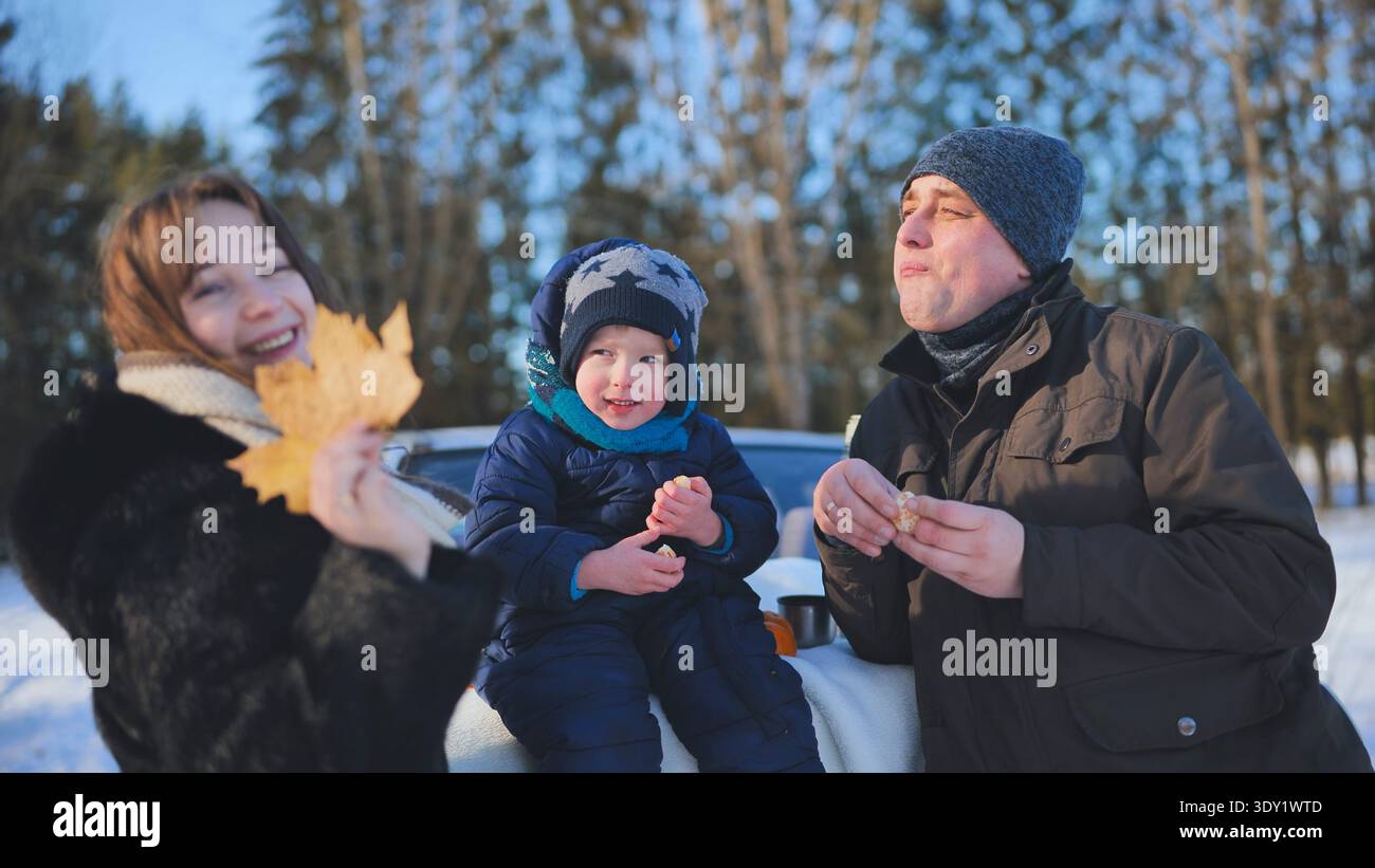 Picknick für die Familie mit Snacks am Straßenrand, parkt in schneebedeckter Waldlandschaft Stockfoto