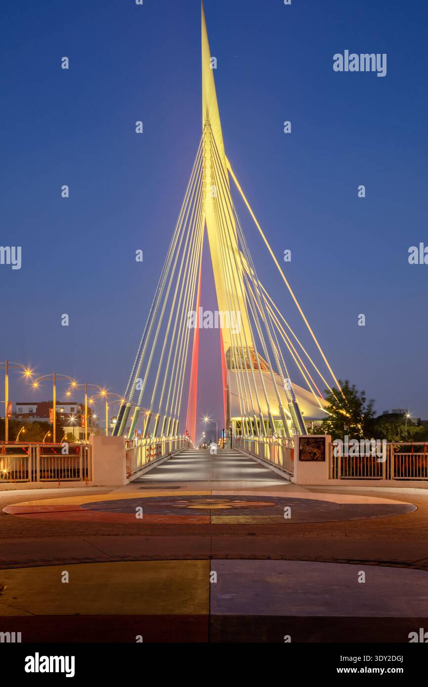 Die Fußgängerbrücke Esplanade Riel überquert den Red River in der Abenddämmerung in der Innenstadt von Winnipeg, Manitoba, Kanada Stockfoto