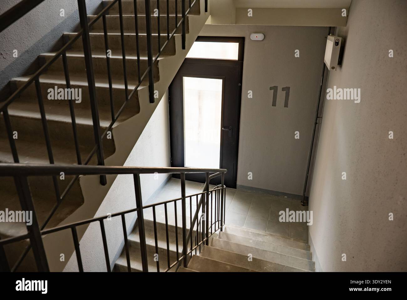Treppe führt zur Wohnungstür mit hellem Licht und Nummer 11 an der Wand Stockfoto