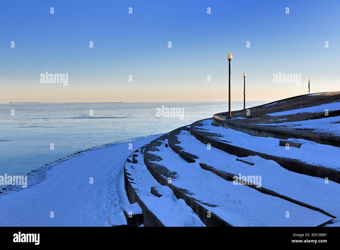Chicago, Illinois, USA. Eine schneebedeckte Seemauer und Eis auf dem Lake Michigan werden kurz nach Sonnenaufgang an einem kalten Wintermorgen gezeigt. Stockfoto