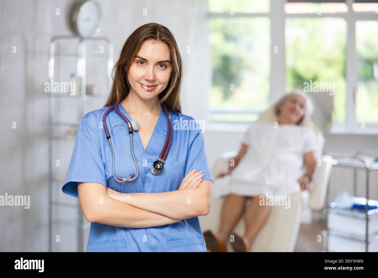 Lächelnde Oberärztin in Uniform mit einer Patientin, die in der Klinik liegt. Stockfoto